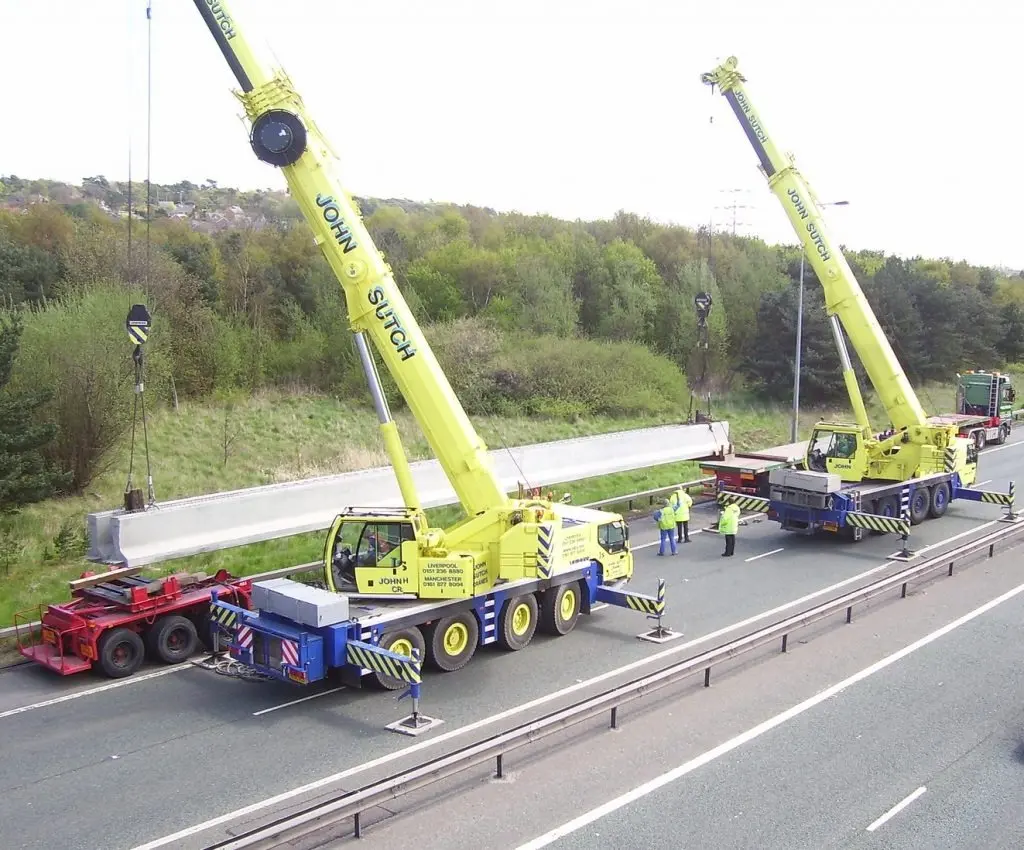 Two cranes lifting road bollard